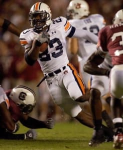 Auburn running back Kenny Irons carries the ball in a white number 23 uniform as South Carolina defenders converge around him.