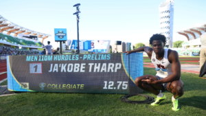 Ja'Kobe Tharp crouches beside the results board after running 12.75 in the men’s 110m hurdles prelims.