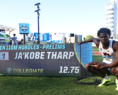 Ja'Kobe Tharp crouches beside the results board after running 12.75 in the men’s 110m hurdles prelims.
