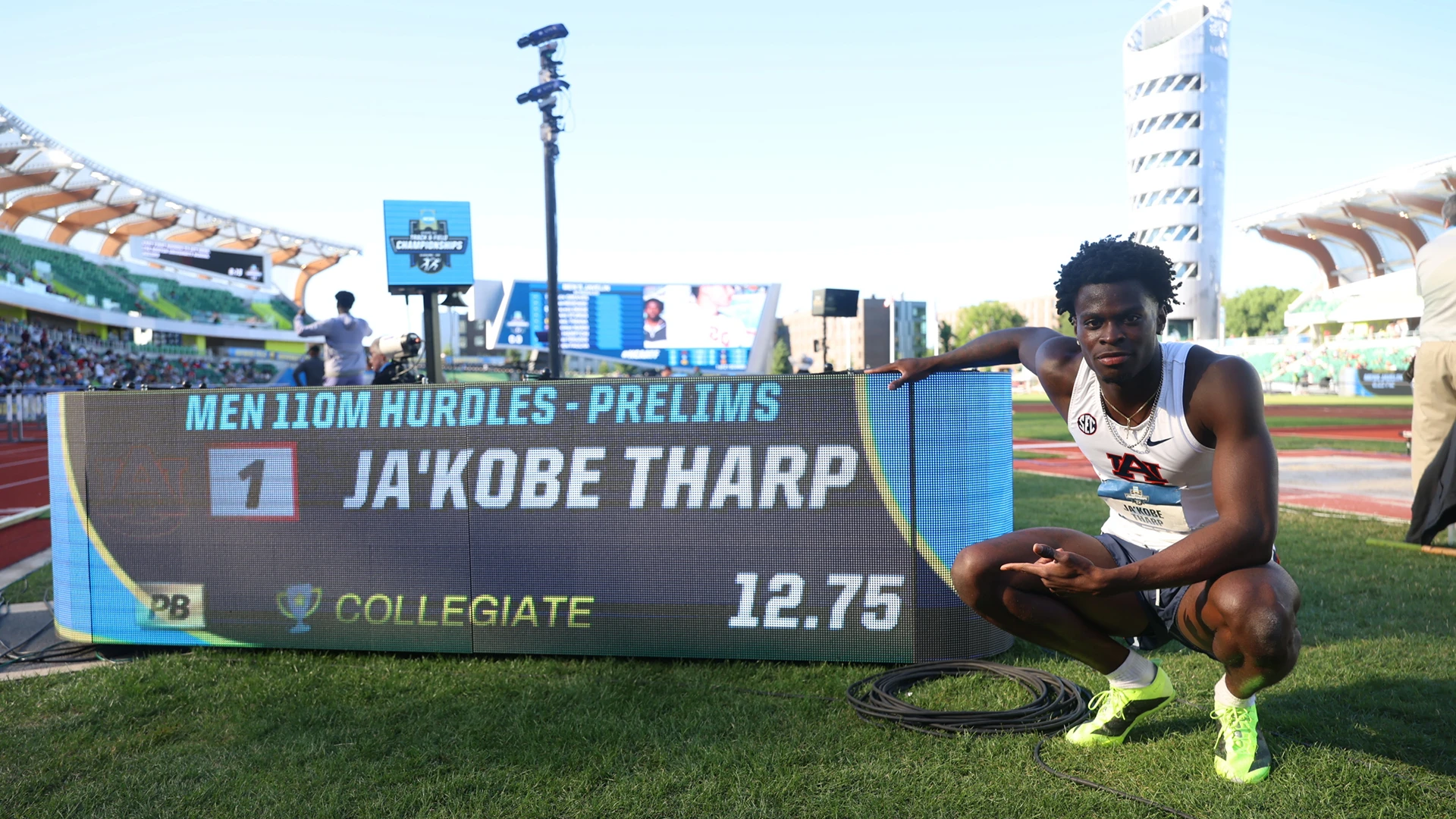 Ja'Kobe Tharp crouches beside the results board after running 12.75 in the men’s 110m hurdles prelims.