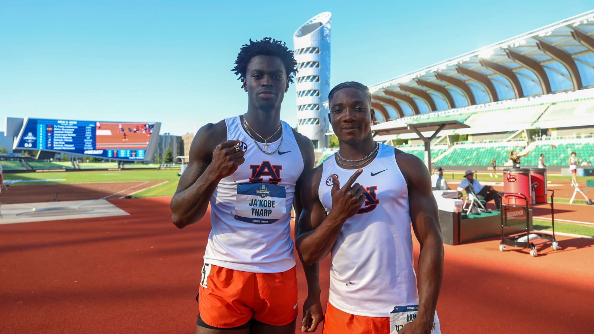 Ja’Kobe Tharp and Kayinsola Ajayi stand on the track in Auburn uniforms, posing at a stadium after their NCAA wins.